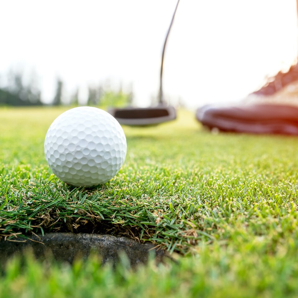 Golfer asian woman putting golf ball on the green golf on sun set evening time.  Healthy and Lifestyle Concept.